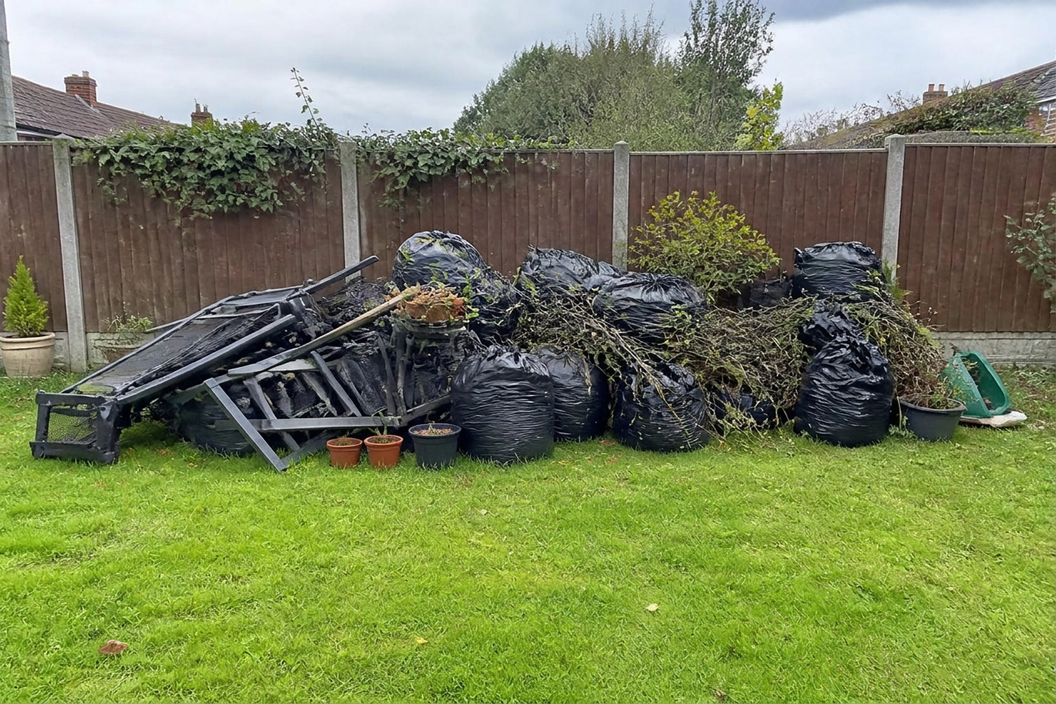 Garden with bagged green waste, old furniture and branches gathered before clearance