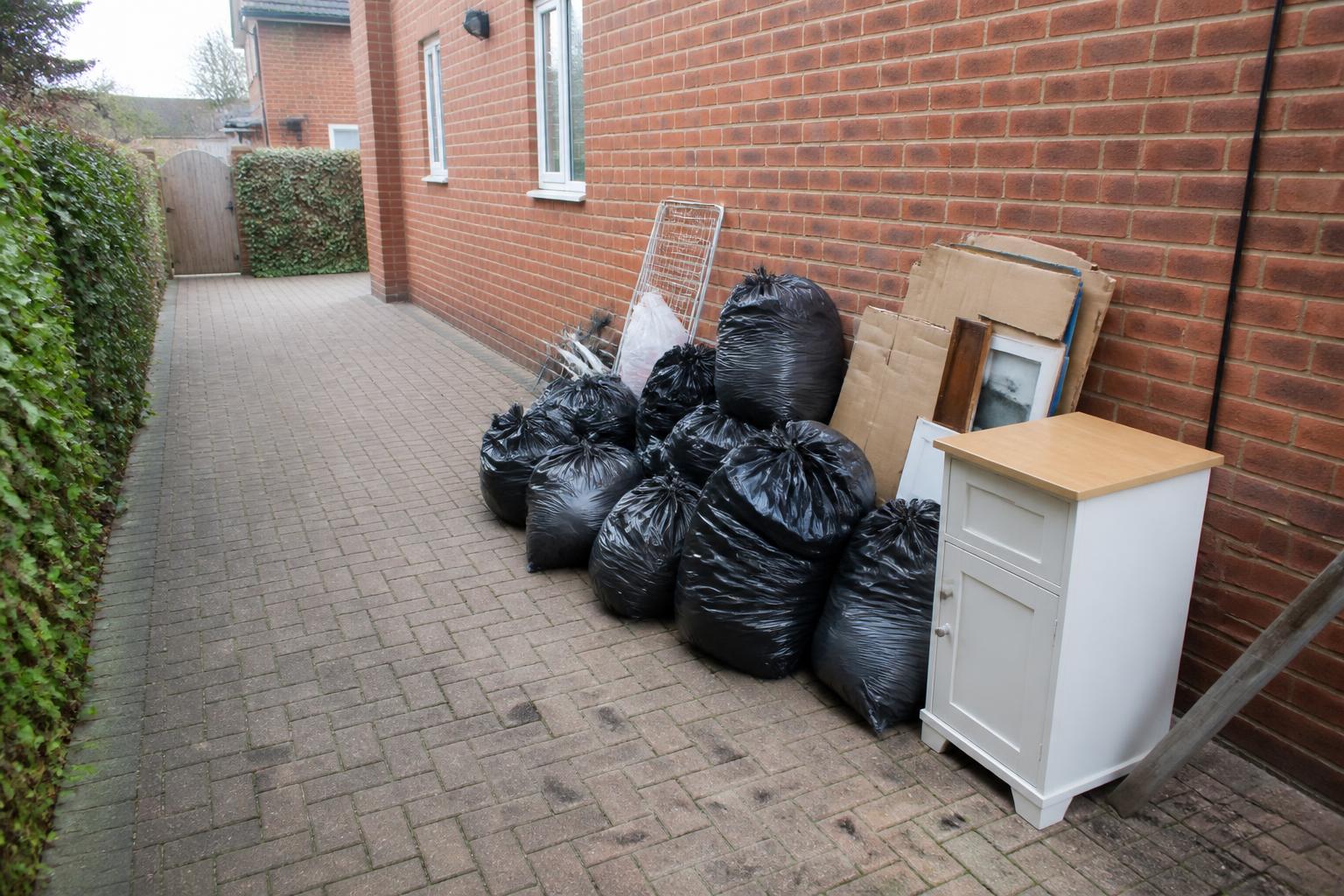 Household waste bags, furniture and cardboard gathered beside a house before collection